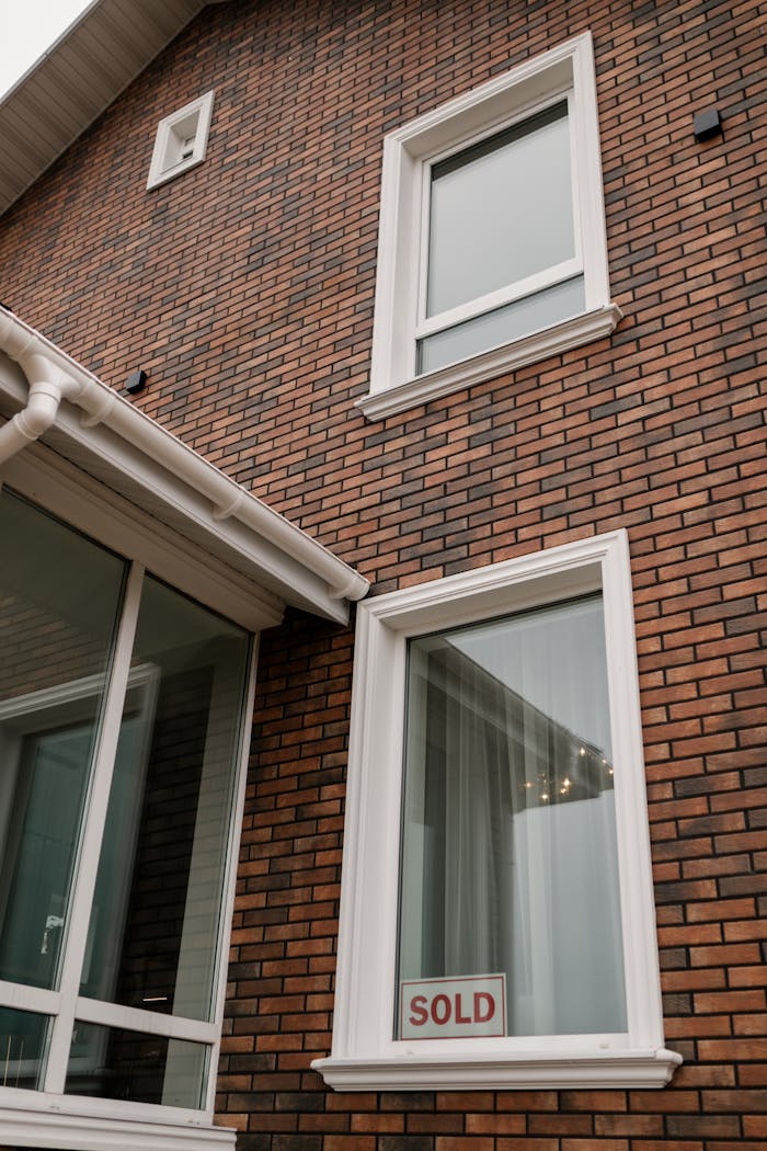 A contemporary brick-faced residential home with a 'sold' sign in the window.